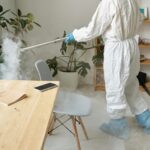 Person in protective suit disinfecting office for virus control.